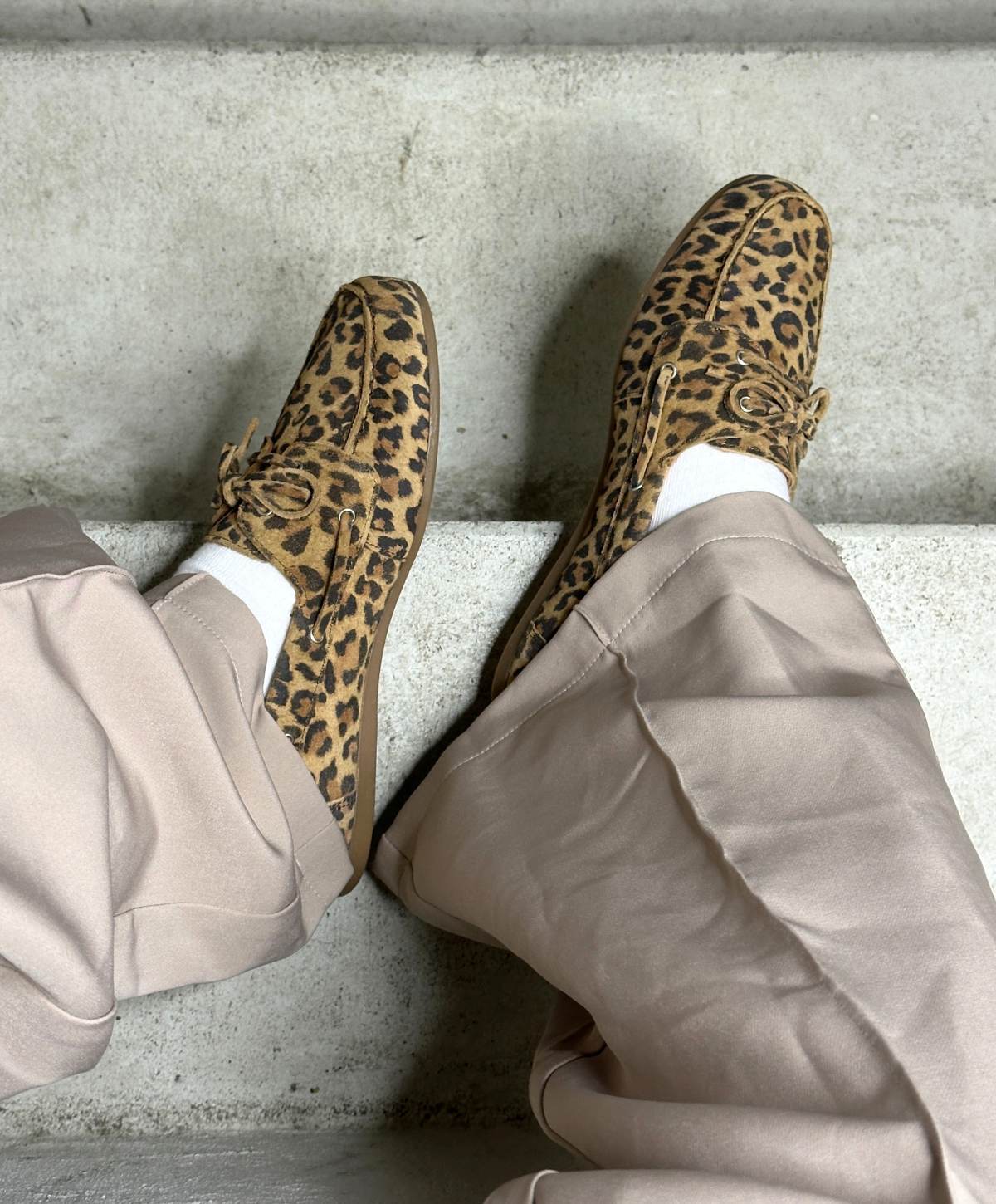 To par leopardmønstrede loafers fra Shoedesign Copenhagen, båret af en person iført lyse bukser og hvide sokker, set ovenfra på en betonoverflade.