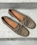 Brune ruskind loafers fra Shoedesign Copenhagen med snørebånd, set ovenfra på en grå betonoverflade.